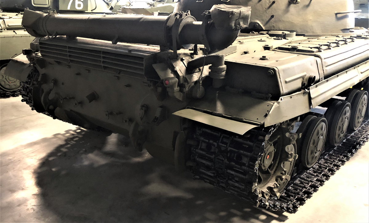 Характерная для машин ранних выпусков решетка выходных жалюзи. Правее виден щиток с сеткой, закрепленный на торце обводного газохода, также характерный для ранних машин. От стенки газохода идет Г- образный патрубок , предназначенный для подогрева масла в масляном баке.