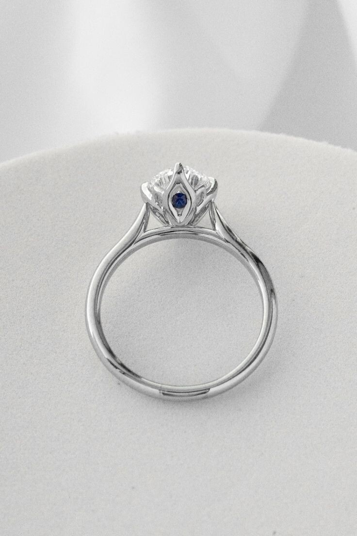 Кафедральный сэттинг позволяет сделать высокую посадку кольца более надежной. Также камень будет меньше цепляться. Обратите внимание, что между крапанами зажат мелкий голубой сапфир. Это называется Peek-a-boo stone (камень-пикабу). Часто такой камень символизирует месяц рождения любимого человека или ребенка