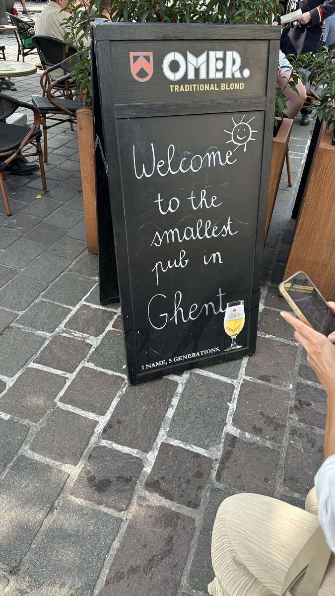 Вывеска гласит: Добро пожаловать в самый маленький паб Гента. Одна фамилия, пять поколений. То есть этим пабом владеет пять поколений одной семьи.