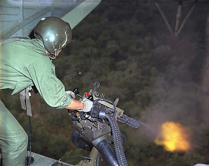 Американский солдат ведёт огонь из M134 Minigun по джунглям с вертолета. Вьетнам