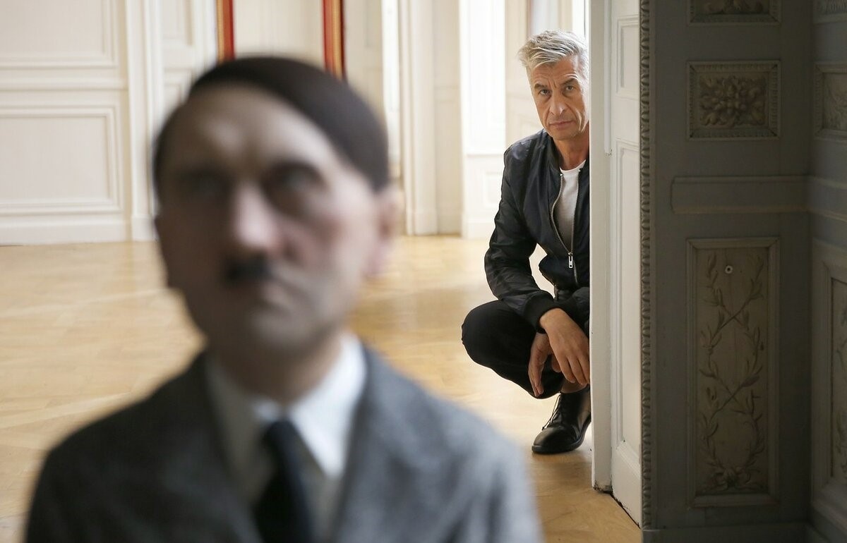 На заднем плане фотографии Маурицио Каттелан, за «спиной» Адольфа Гитлера.
