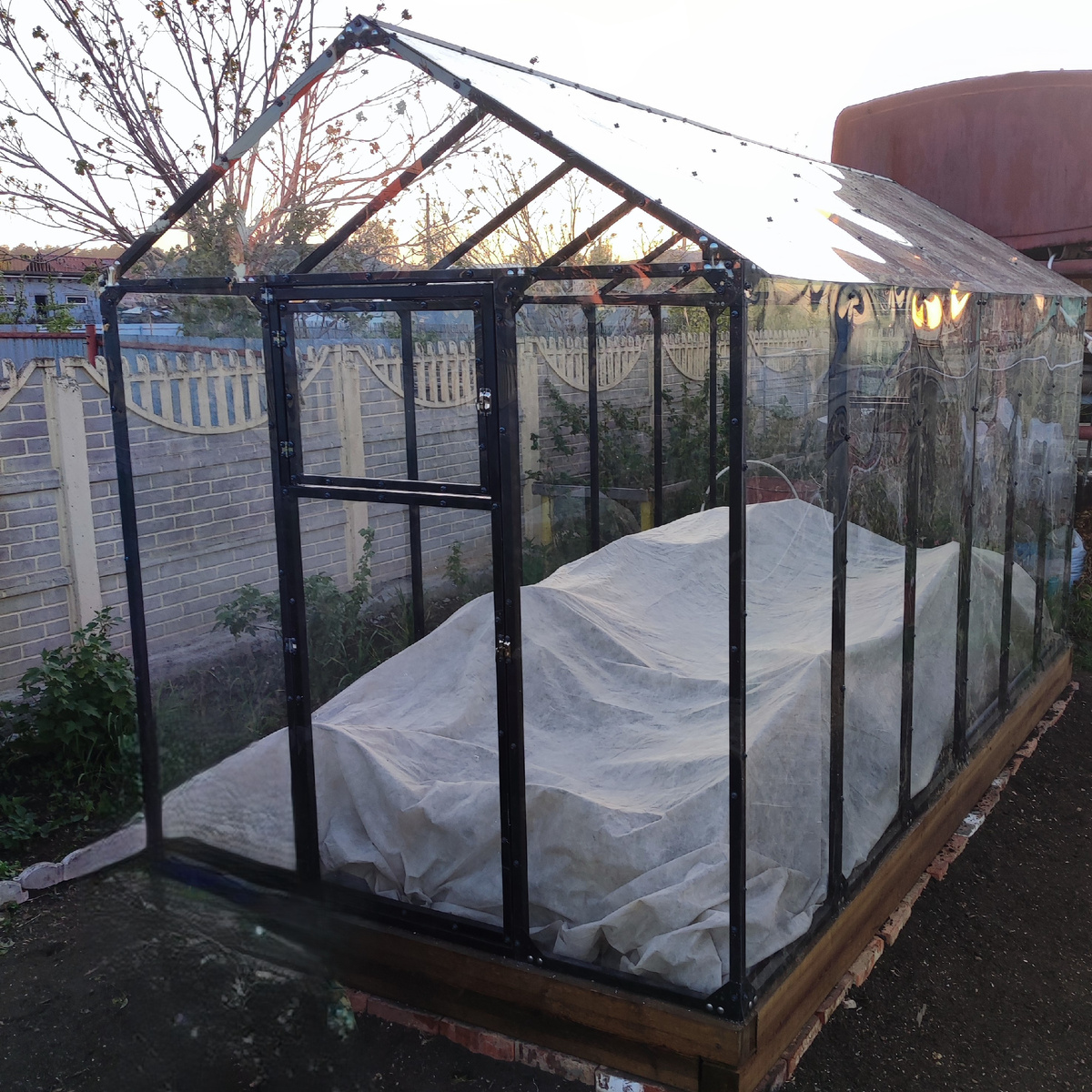 Теплица домиком или в английском стиле с обшивкой из монолитного поликарбоната.