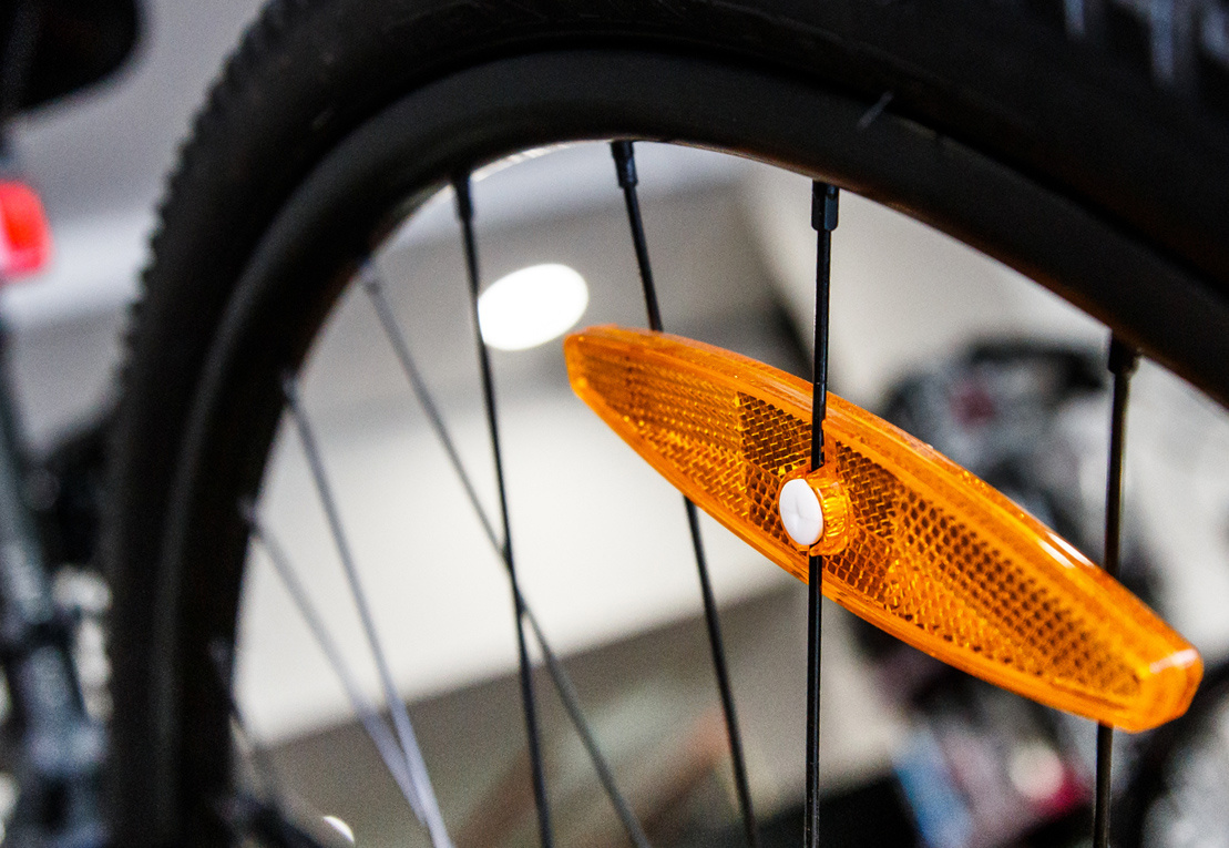 Пластиковый оранжевый катафот на колесе велосипеда