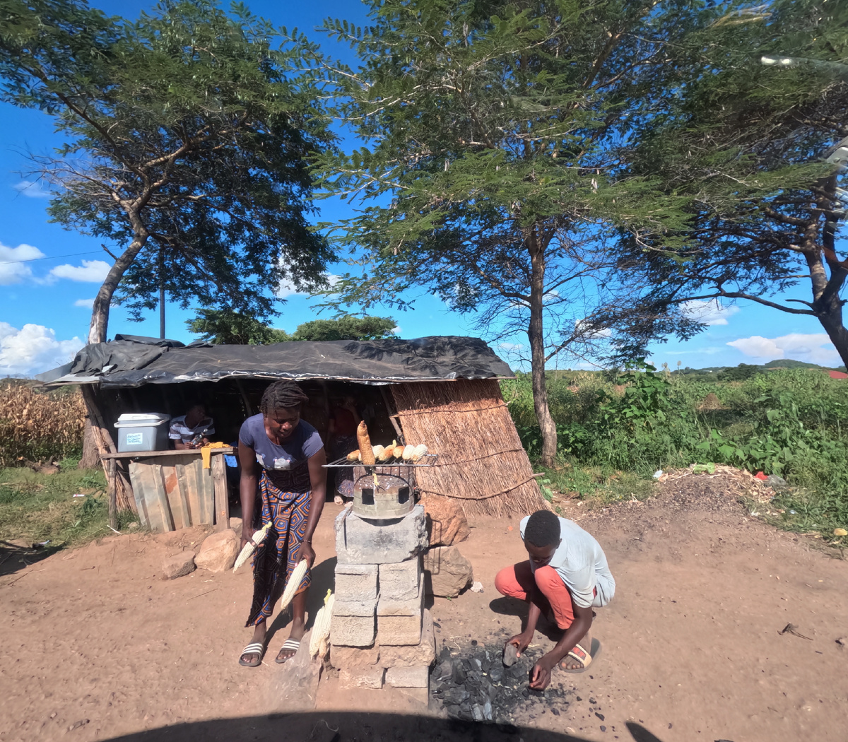  Люди продают кукурузу приготовленную на углях.