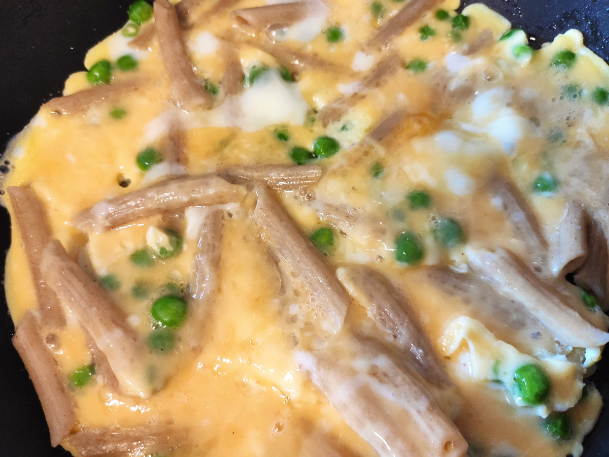 Цельнозерновые макароны и зелёный замороженный горошек залитые яйцом