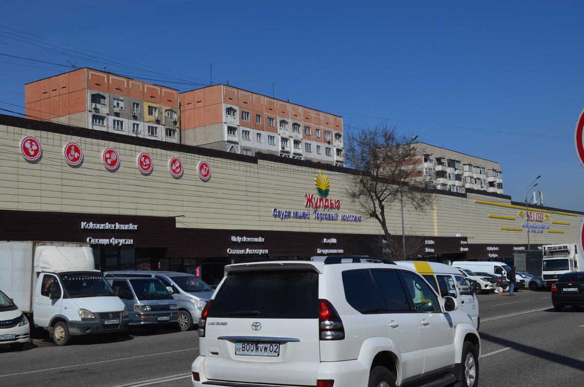 Это рынок "Жулдыз", часть чьих павильонов находится под крышей здания, есть и несколько контейнеров на улице.