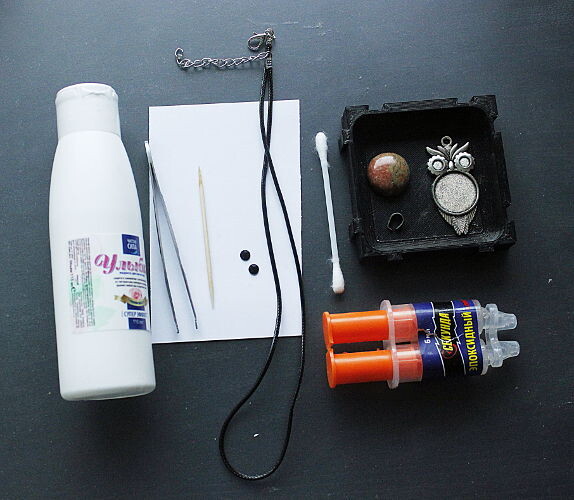 Материалы: растворитель (можно жидкость для снятия лака, ацетон или другой), пинцет, зубочистка, лист бумаги примерно 5-10см, два черных клеевых страза 4мм для глазок, готовый шнурок, ватная палочка, кабошон 20мм, держатель-петелька для кулона, основа для кулона с сеттингами 20мм и 2х4мм, эпоксидный клей. Для установки держателя еще желательно круглогубцы.