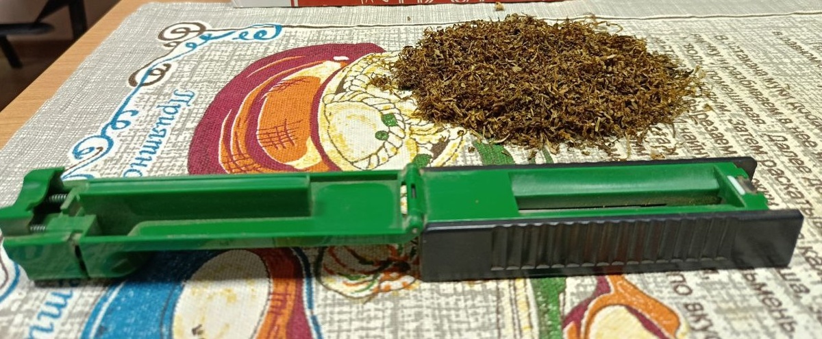 Раскрытая забивочная машинка рядом с табаком на развес