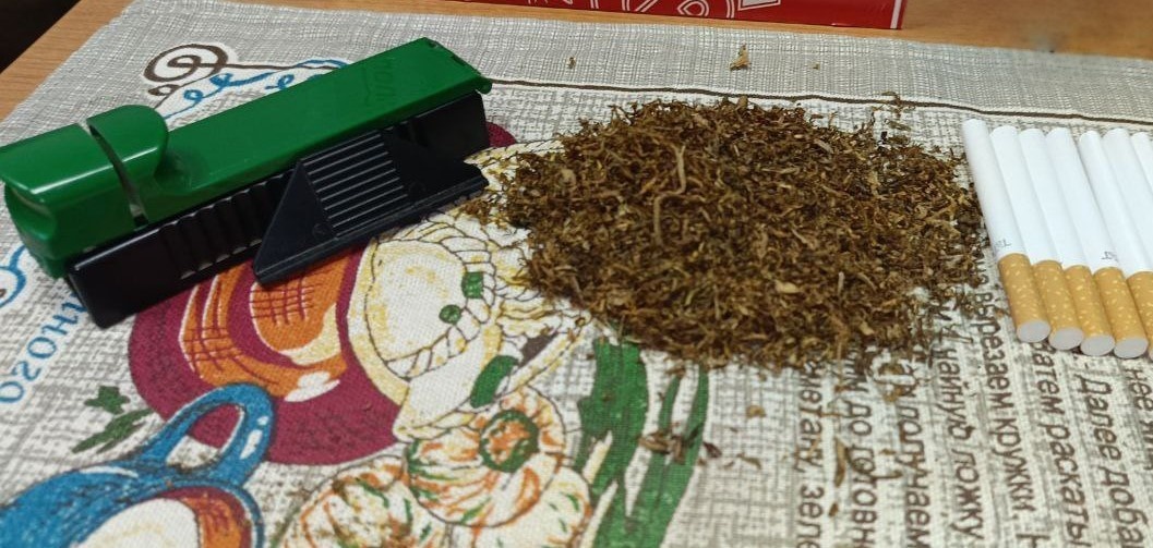 Зеленая ручная машинка рядом с табаком и пустыми гильзами