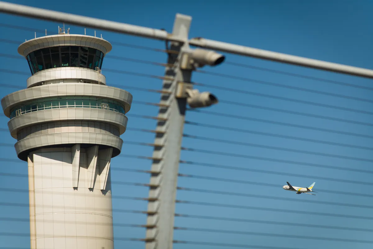 Самолёт пролетает мимо диспетчерской вышки во время взлёта. Фото: Bloomberg