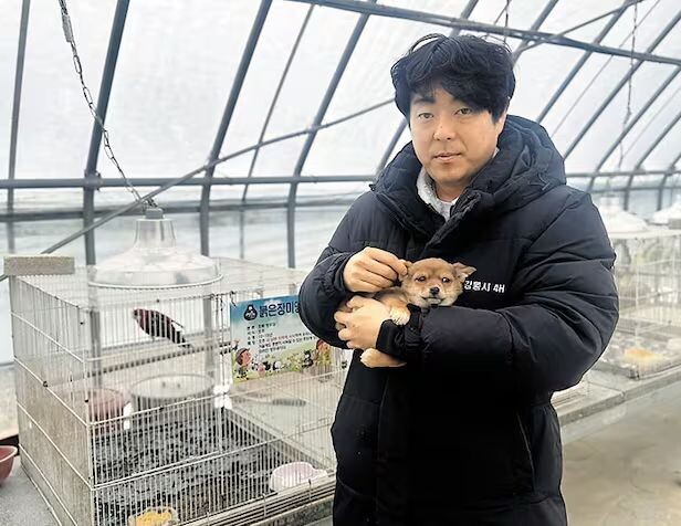    Владелец Twin Animal Farm Нам У Сон держит спасенную собаку в крытом вольере своей фермы в Канныне, провинция Канвон, 6 марта.