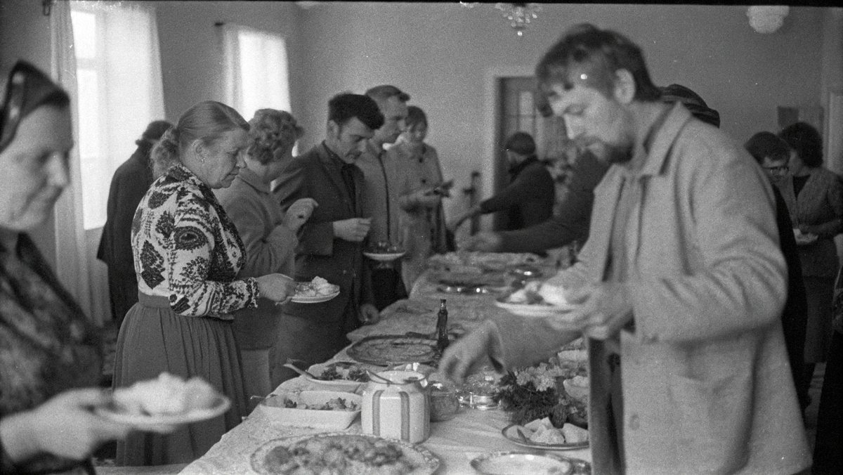 Гости угощаются за столом в зале родительского дома