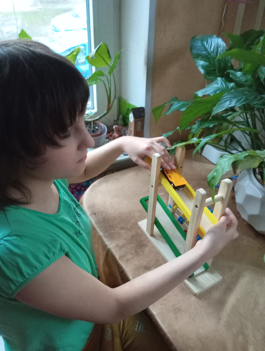 Незрячий ребенок играет в машинки.