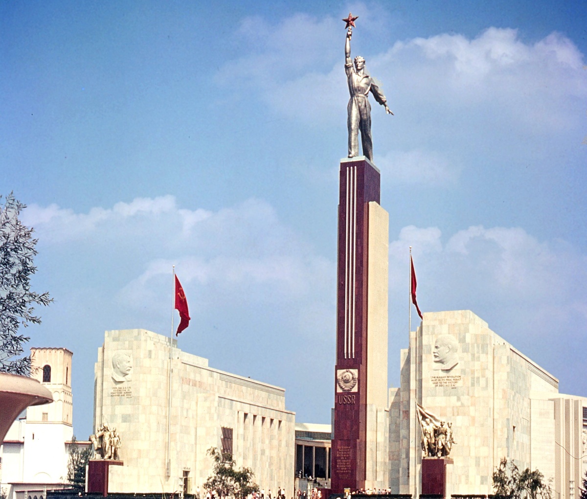 Павильон СССР на Всемирной выставке 1939. В центре — пилон Сталинской Конституции со скульптурой В.А. Андреева "Новый советский человек". На торцах здания — дополненные изречениями барельефы Сталина и Ленина работы С.Д. Меркурова. Под ними — скульптурные группы героики социалистического строительства и гражданской войны работы М.Г. Лысенко и Л.Д. Муравина. Фото: https://www.flickr.com/photos/francispmurphymuseum/27204079135/in/album-72157667885240210