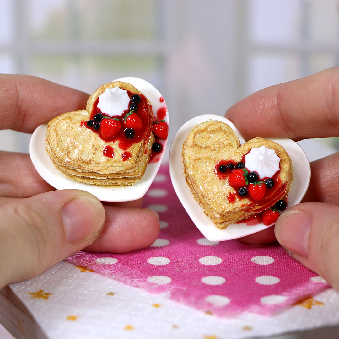 Блинчики в форме сердца с капельками варенья на тарелке