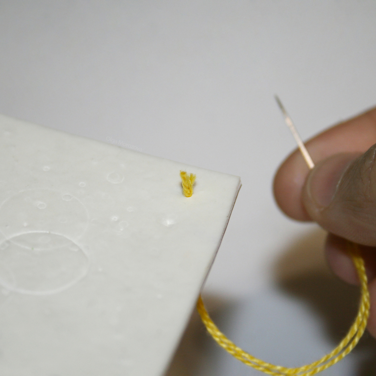 Протягиваем иголку и нитку через линолеум, оставляя небольшой кусочек нити торчать.