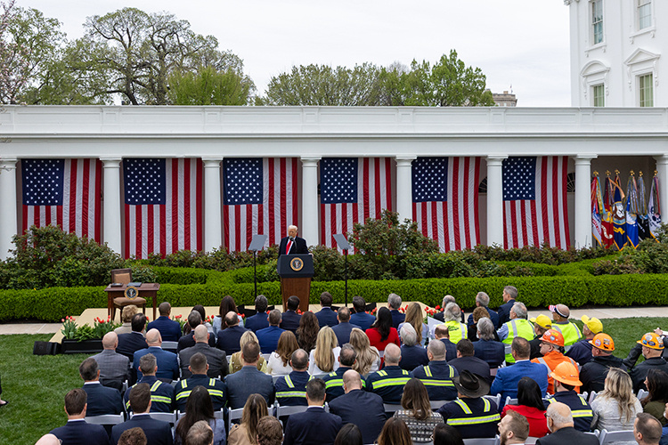    Выступление прошло в Розовом саду Белого дома в окружении «9 гигантских флагов США» перед кабмином и «толпы профсоюзных рабочих в касках и флуоресцентных строительных жилетах».   
Фото: © Hu Yousong / XinHua / www.globallookpress.com