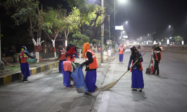 Женщины в дорожных жилетах ночью метут улицы
