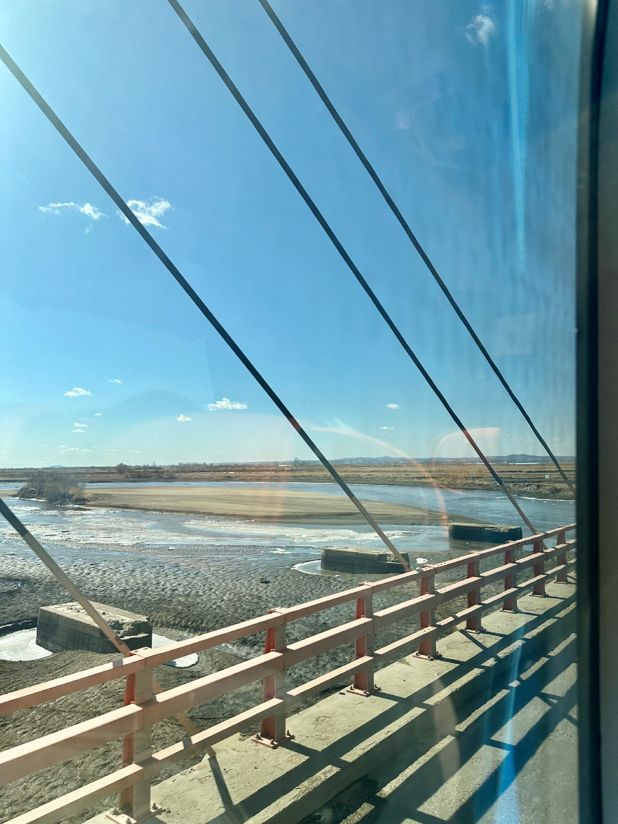 Вид из окна автобуса на еще замерзшую реку и рисовые поля на пути в Мишань