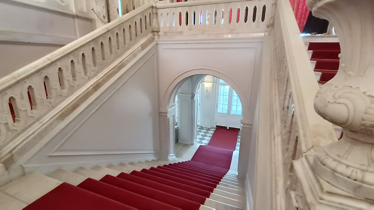 На лестнице ковёр красного цвета, на окнах занавесы такого же оттенка. Эти яркие акценты дают дополнительную роскошь и пышность интерьеру