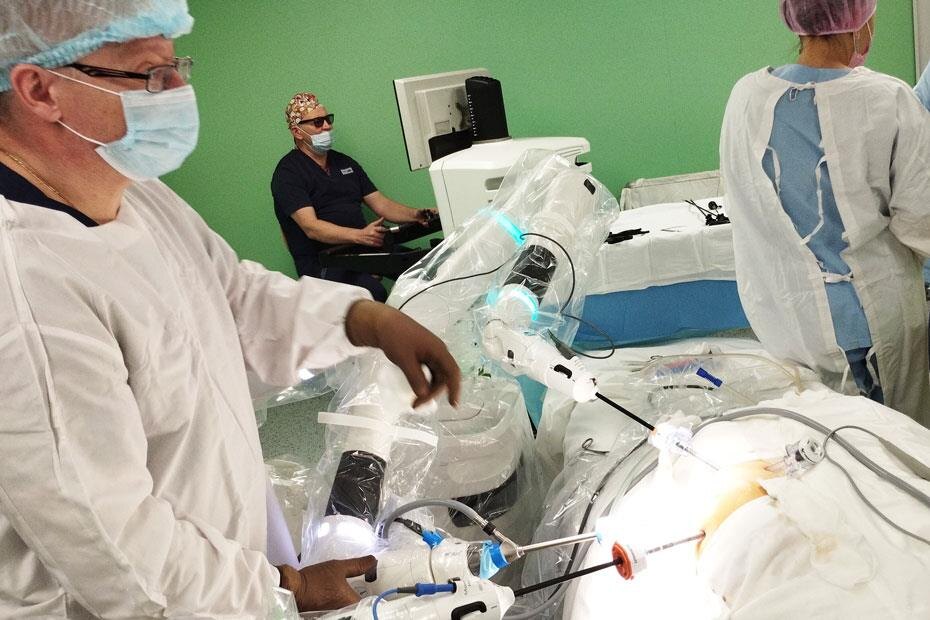 Юрий Козлов (на заднем плане), хирургический робот (в центре и в нижней части фото) и живые ассистенты. Фото Алексея Каменского