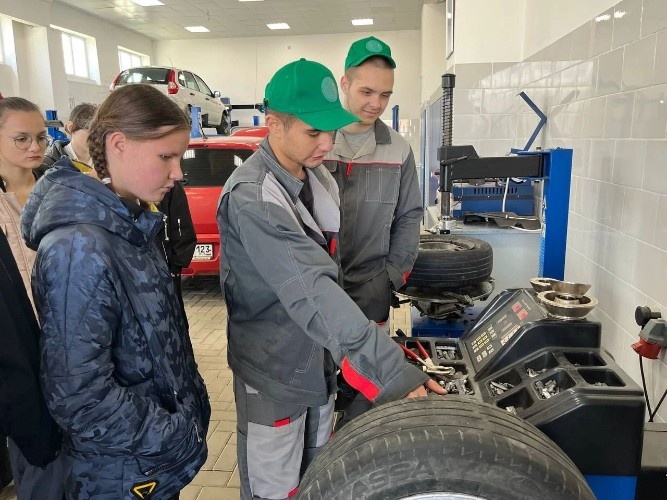    студент Ладожского аграрного показывает школьникам балансировку колеса на спецоборудовании