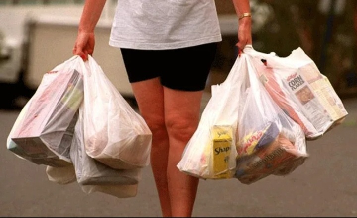 Женщина тащит большое количество продуктов домой что бы накормить свою семью.