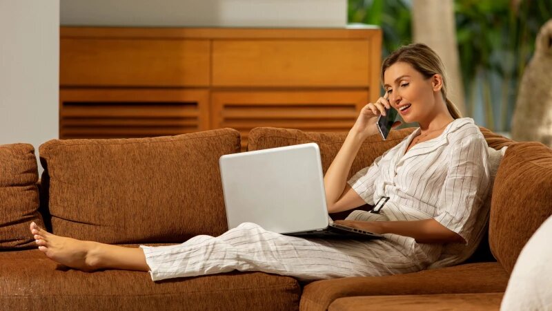     Женщина работает на ноутбуке и разговаривает по телефону. Фото: ru.freepik.com, автор alexeyzhilkin.