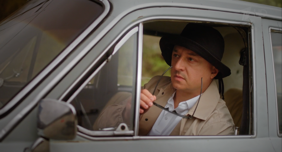 Максим Лагашкин в роли Джеймса Бонда и в шляпке. Кадр из сериала "Ищейка-8"