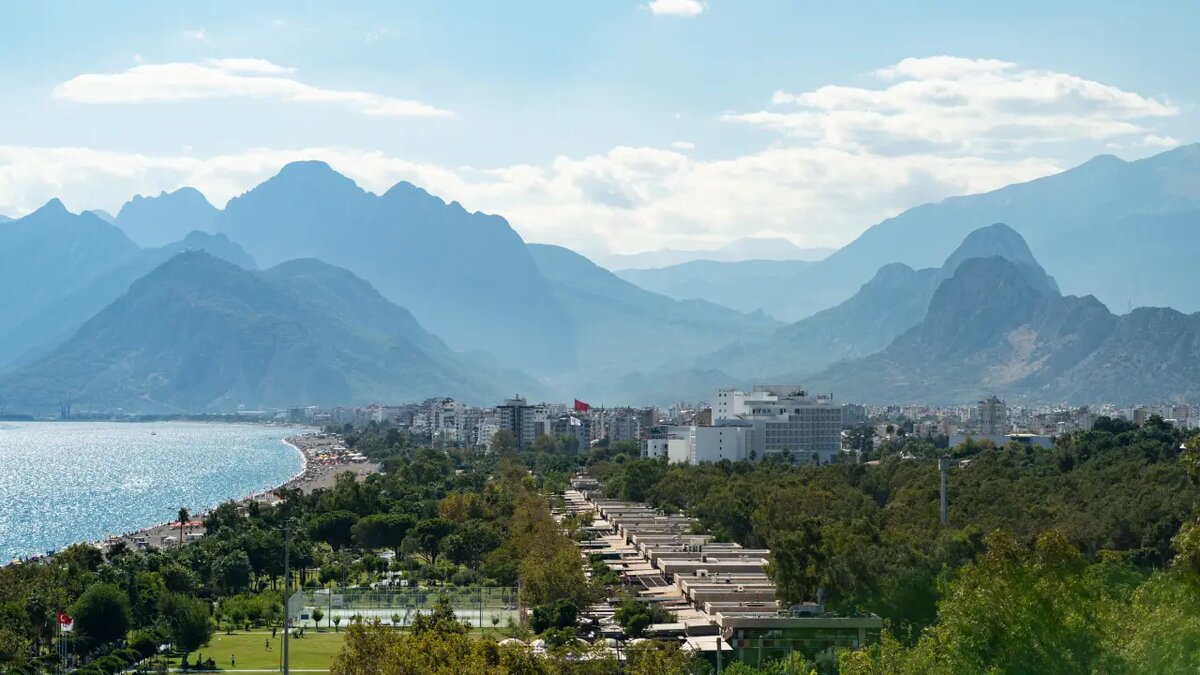 Турция. Вид с воздуха на турецкий курорт Коньяалты с гостиничными зданиями среди высоких деревьев недалеко от пляжа