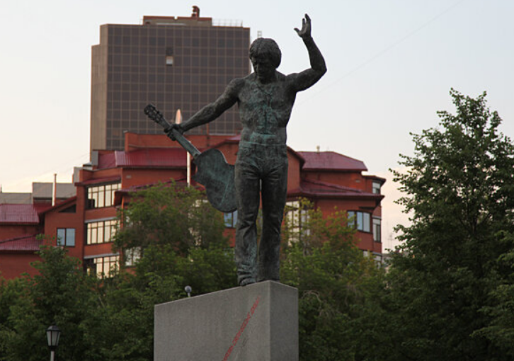 Памятник Владимиру Высоцкому в Новосибирске



История создания памятника полна интересных деталей. Изначально победителем конкурса стал новосибирский скульптор Геннадий Парамонов, но в итоге работу поручили Тартынову. Рассматривалась даже кандидатура друга Высоцкого - Михаила Шемякина, но его гонорар в 2 миллиона долларов оказался неподъемным.

Особую атмосферу памятнику придавала бронзовая деталь - череп "бедного Йорика" у основания. К сожалению, после нескольких краж он бесследно исчез.

Хотя Высоцкий никогда официально не выступал в Новосибирске, он неоднократно бывал в городе. Об этом свидетельствуют записи его коллег - актера Валерия Золотухина и режиссера Станислава Говорухина. Автограф поэта до сих пор хранится у вдовы художника Николая Грицюка.

На открытии памятника присутствовал сын поэта Никита Высоцкий. Инициатор проекта Анатолий Олейников восемь лет собирал средства на его создание. Скульптор объяснил позу Высоцкого как прощальную - будто поэт, уходя, оставляет людям свою гитару и песни.

Интересный эпизод произошел во время церемонии открытия. У подножия памятника появился огромный букет в виде математического знака интеграла - символ Академгородка. Из-за опечатки на ленте получилась загадочная фраза: "Вы... под интегралом", что многие восприняли как тонкую иронию, достойную самого Высоцкого.

Этот памятник стал важной частью культурного ландшафта Новосибирска. Еще в 1985 году здесь 