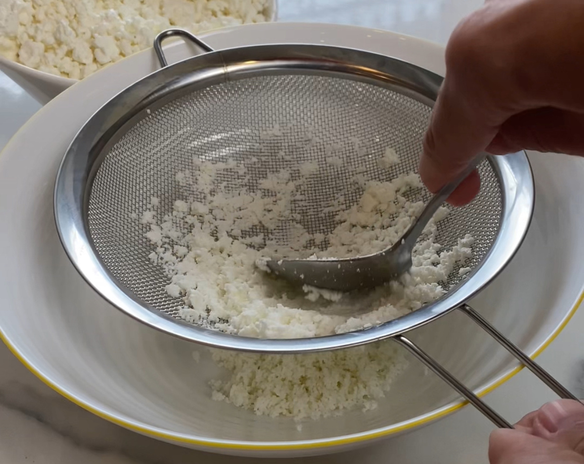 Перетереть творог через сито.