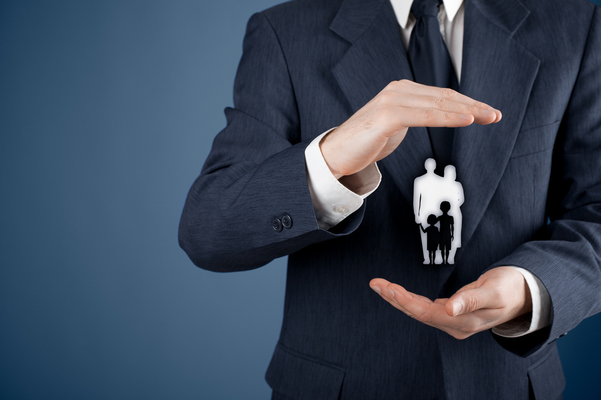 Медицинская страховка в США — фото страхового агента, укрывающего силуэт семьи