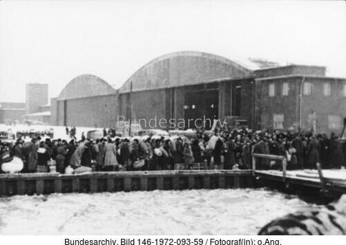 Пиллау.- На пристани в Пиллау-Нойтифе (на реке Фрише-Нерунг) беженцы ждут посадки на корабль перед ангаром аэродрома Люфтваффе.