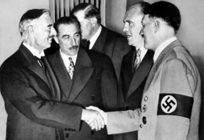 Дружеское рукопожатие Гитлера с премьер-министром Англии Невиллом Чемберленом в Мюнхене 30 сентября 1938 г. День, когда премьеры Франции и Англии подписали Мюнхенское соглашение, определившее судьбу Чехословакии. Рядом с Чемберленом стоит сэр Невилл Хендерсон, посол Великобритании в Германии. Пауль Шмидт, переводчик, — рядом с Гитлером.