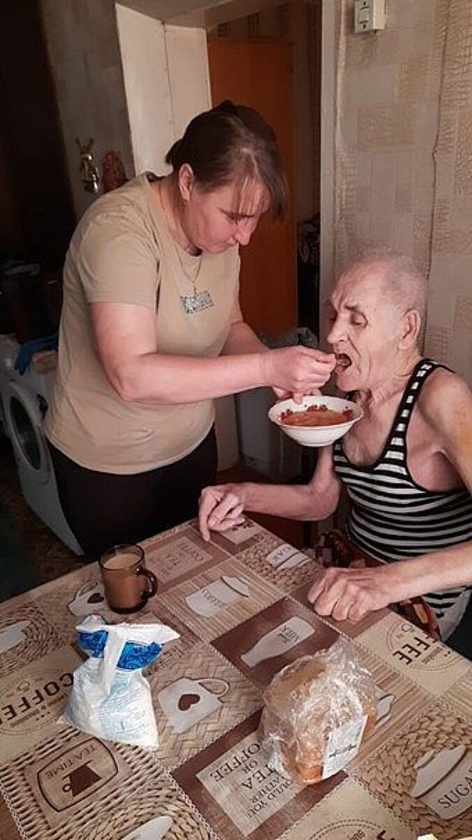 Соцработница кормит пожилого мужчину