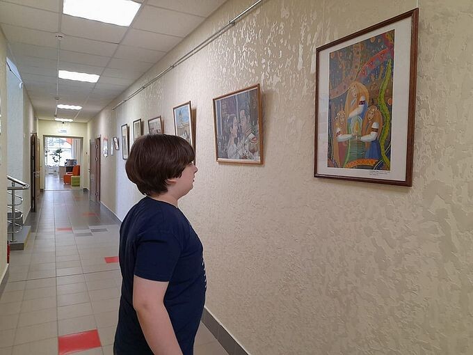 Мальчик-подросток разглядывает картину на стене