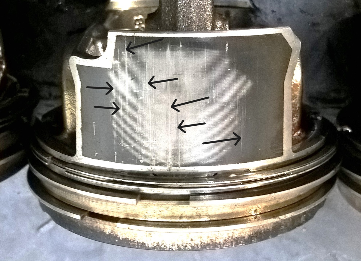 Фото 2. Множественные вертикальные царапины на юбке поршня показаны стрелками.