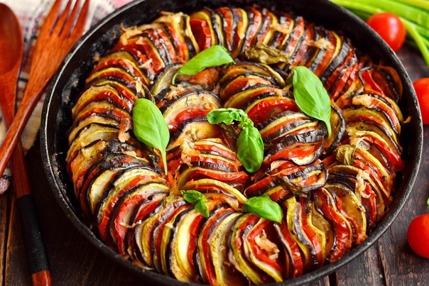 Ингредиенты

2 баклажана среднего размера

2 кабачка

1 красный болгарский перец

1 жёлтый болгарский перец

1 зелёный болгарский перец

4 спелых помидора

1 большая луковица

3-4 зубчика чеснока

3-4 столовые ложки оливкового масла

Соль и перец по вкусу

1 чайная ложка сахара (по желанию)

Прованские травы (тимьян, розмарин, лавровый лист, базилик)


Шаги по Приготовлению

Подготовка Овощей: Вымойте все овощи. Нарежьте баклажаны и кабачки тонкими кружочками. Перцы очистите от семян и нарежьте на полоски. Помидоры также нарежьте кружочками. Лук нарежьте полукольцами, а чеснок измельчите.


Соте Луковых и Чесночных Основ: В большой сковороде нагрейте две столовые ложки оливкового масла на среднем огне. Добавьте лук и чеснок, обжаривайте до прозрачности — около 5 минут.


Соус: Добавьте к луку часть нарезанных помидоров. Приправьте солью, перцем, прованскими травами и сахаром (если используете). Готовьте, пока помидоры не начнут развариваться, превращаясь в соус.


Слои Овощей: Разогрейте духовку до 180°C. В жаропрочной форме для запекания распределите слой томатного соуса. Сверху уложите чередующиеся кружки баклажанов, кабачков и помидоров вертикально, создавая красивый узор. В промежутки добавьте полоски перцев. Посолите и посыпьте травами.


Завершение и Выпекание: Слегка полейте овощи оливковым маслом. Накройте форму пергаментной бумагой или фольгой. Запекайте в духовке около 40-50 минут, пока овощи не станут мягкими.


Подача: Дайте рататую настояться 10 минут перед подачей. Подавайте его как отдельное блюдо или гарнир. Блюдо отлично сочетается с белым вином и хрустящим багетом.