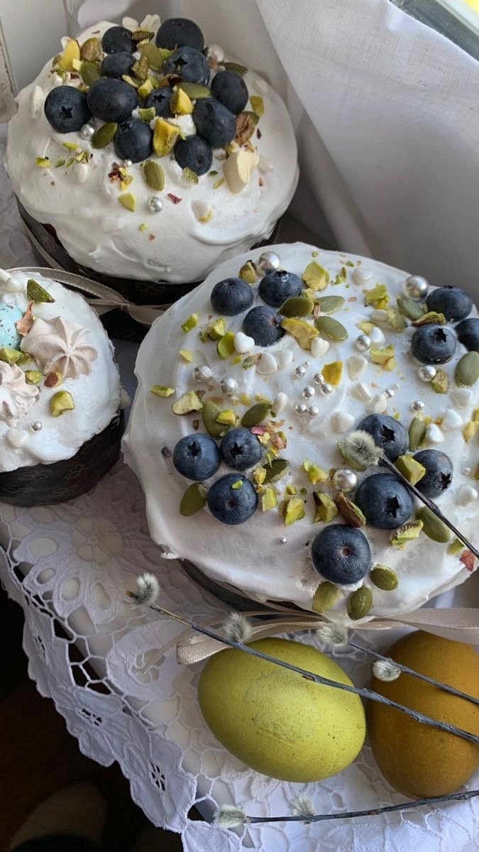 Куличи с белой глазурью, украшенные голубикой и фисташками