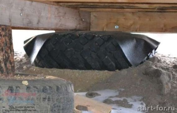 Автомобильная шина под легким деревянным домом