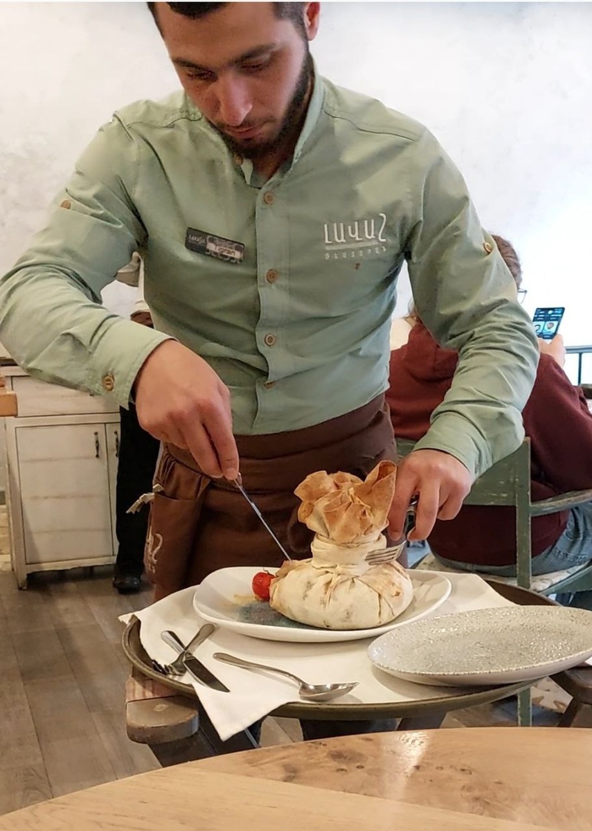 Блюдо называется "хурджин": ягнятина, болгарский перец, помидор, соус, лук, зелень, специи, и все это завернуто наподобие гигантского хинкали в большой лаваш