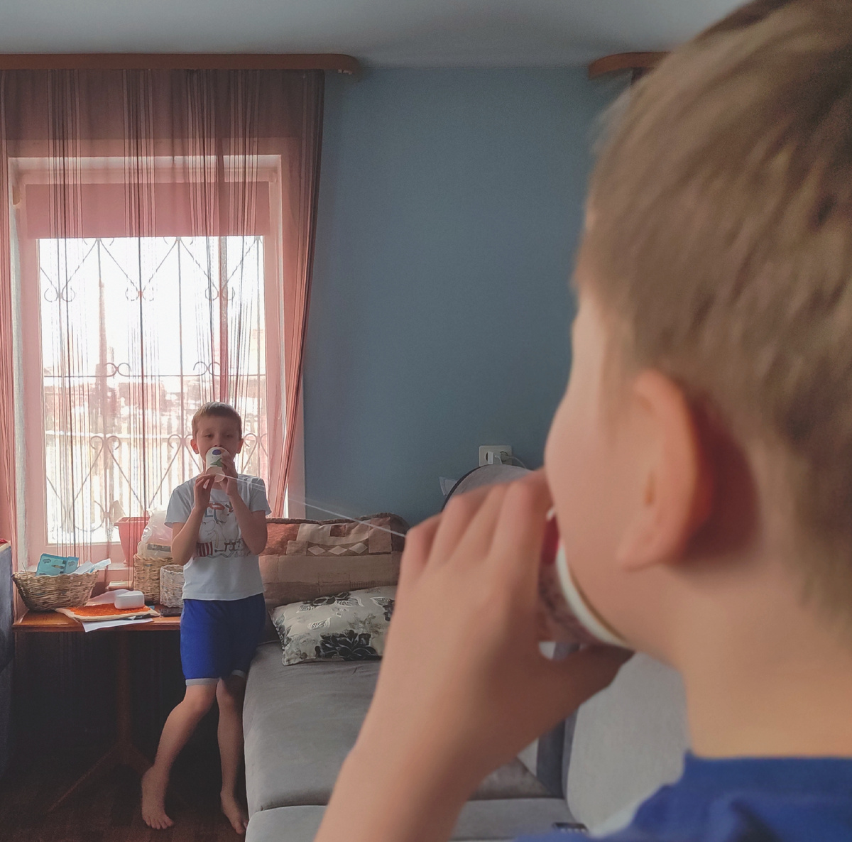 2025 год, мои дети изобрели телефон из бумажных стаканчиков и нитки. Это так на фото получилось, Вадюха просто не успел свою трубку к уху поднести