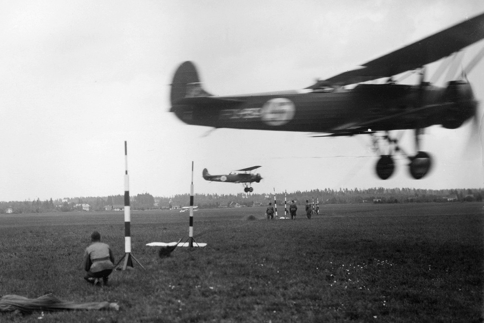 Эскадрилья Fokker C.V на лету перехватывает сообщение. Пилоту нужно было словить опущенным крюком веревочную петлю между шестами высотой не более 5 метров. Фото: Ilmavoimat / Suomen Ilmailumuseo.