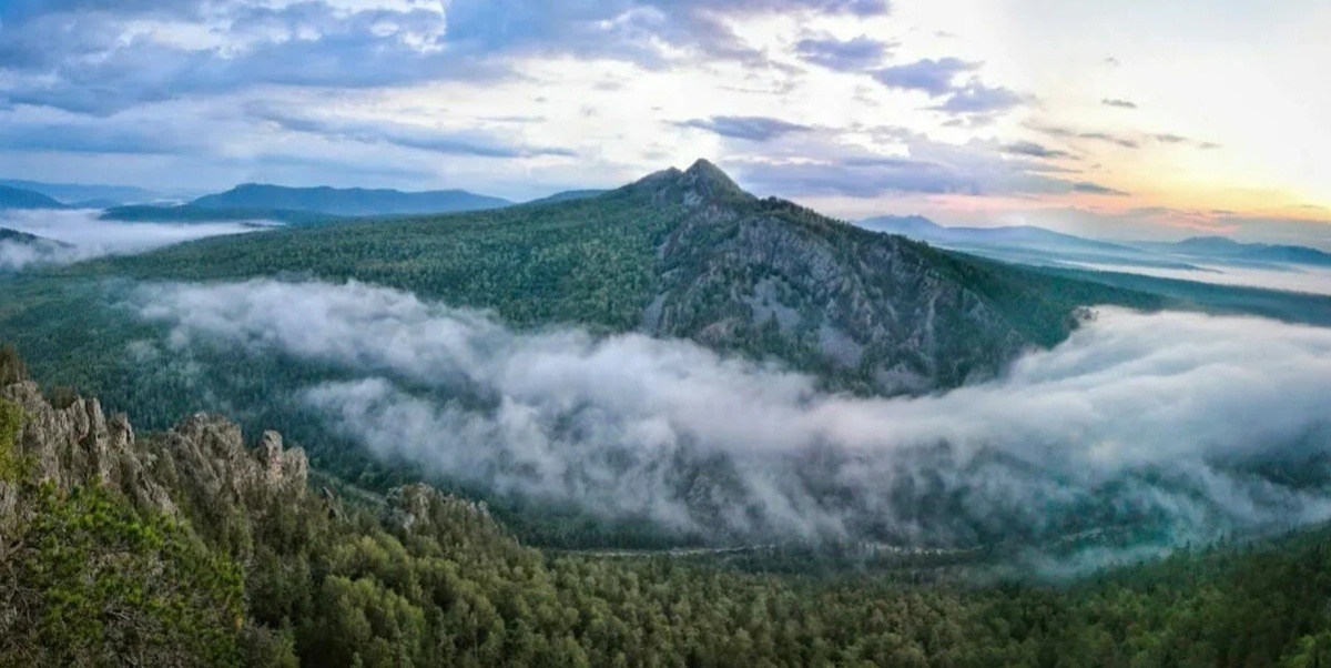 Гора Ямантау представляет собой сочетание красоты и тайны. Эта могучая гора высится, разделяясь на две вершины – Большой Ямантау высотой 1640,4 м, а также Малый Ямантау, высота которого составляет 1512,7 м. Обе вершины обширны и характеризуются разнообразием ландшафта, который формировался под воздействием морозного выветривания и солюфлюкции – таяния грунтов при промерзании. На южных склонах создаются ступенчатые пейзажи, в то время как северные характеризуются крутыми и расчленёнными склонами. От подножий до 900–1200 м простирается горный темнохвойный пояс, а выше – криволесья и стланики с каменистыми участками. Высоко расположенный Гольцово-Тундровый пояс оставляет особенно яркое впечатление своей красочной растительностью.Однако выше 1100 м уже открывается совершенно другой мир. На склонах, покрытых разнообразным Курумником, растут цветы и мхи, создавая уникальный ландшафт.На вершине же, украшенной глыбами кварцитов и песчаников, тайны природы переплетаются со следами человеческой деятельности. Тут есть родники с маленькими прудами, а также плато усыпано следами былых времен – металл, строительные леса, остатки водопровода, бетонный фундамент.Окружённая охраняемой зоной, эта знаменитая гора остается неприступным символом природной величины и загадочной истории.