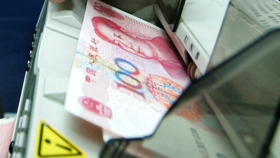    Машинка для счета купюр. Служащий банка считает юань. Автор фото: REUTERS