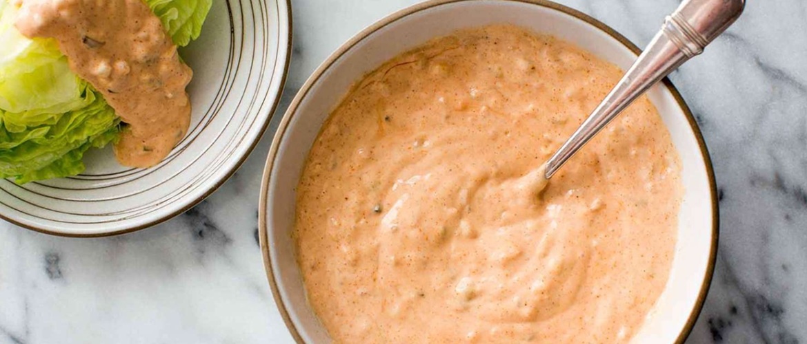 Домашний соус тысяча островов в светлой керамической миске с ложкой, рядом листья салата айсберг, политые соусом - пошаговый рецепт