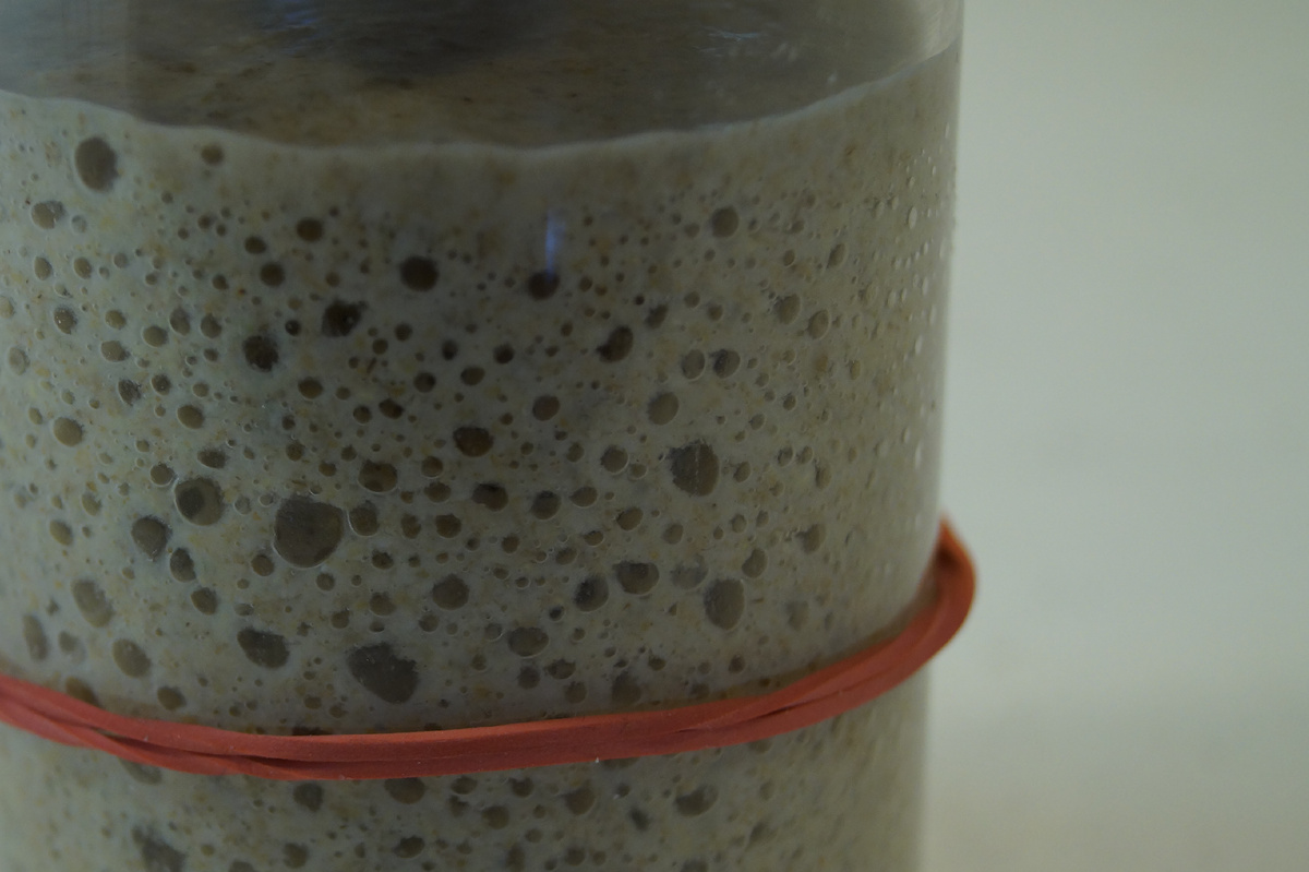 Ржаная закваска пузырится с прозрачной банке с маркером подъема