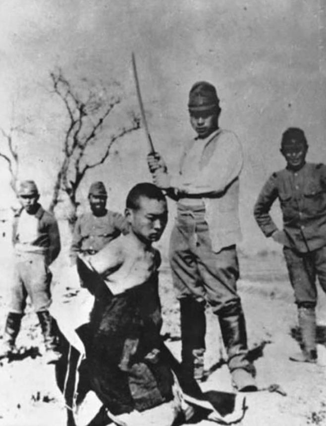 Молодой китайский гражданин стоит на коленях, заложив руки за спину, и ожидает казни через обезглавливание от рук японского солдата во время Нанкинской резни.
Wikimedia Commons