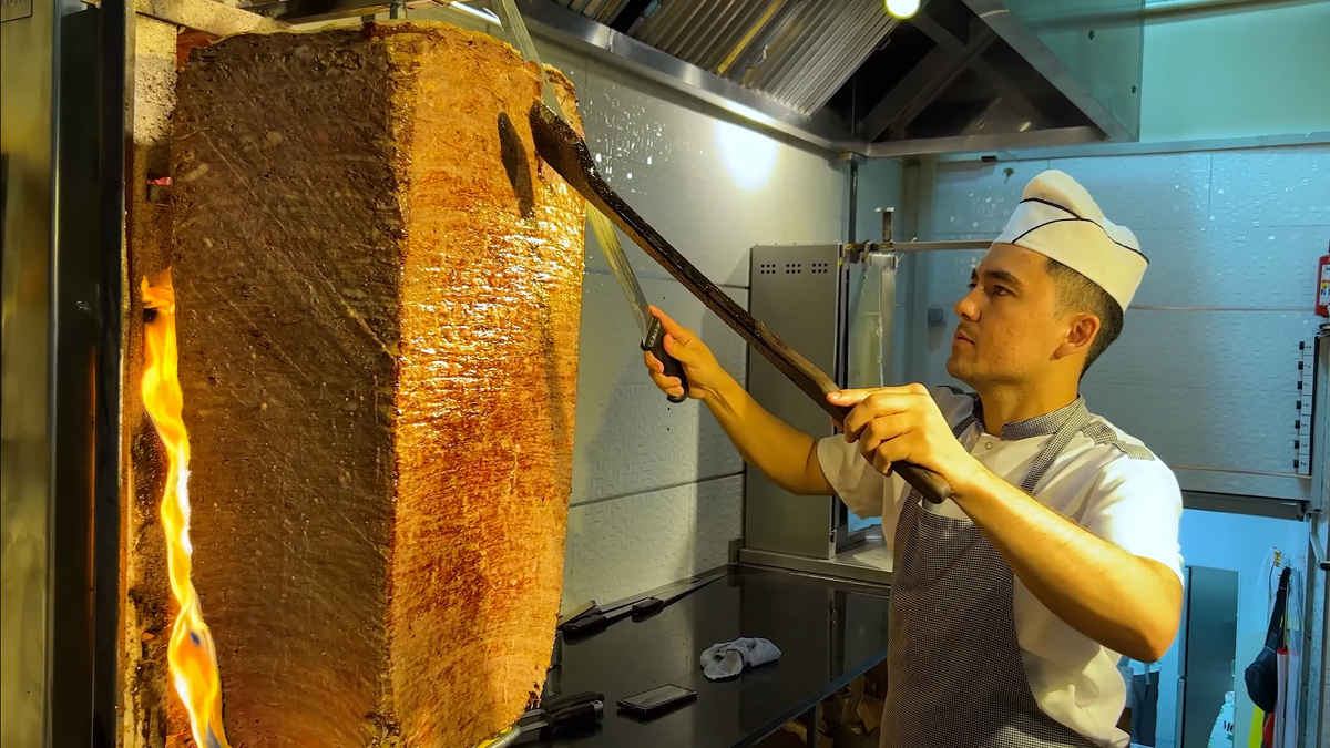 Кадр из видео, процесс срезания мяса с вертеля